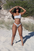 A woman wearing a Silber asymmetrical bikini top and the matching bottom at the beach.