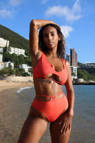 A woman in a red Highways bikini infront of the beach.