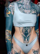 A asymmetrical silver bikini top with the matching silber bottom on a fully tattooed model.