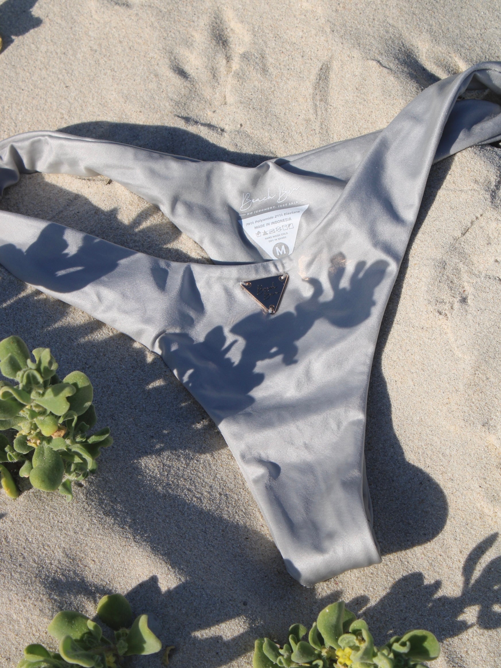 A silber V cut bikini bottom on the sandy beach.