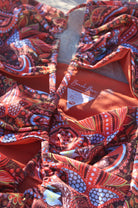 A close up of a  multicolored floral swimsuit with an asymmetric cut-out neckline and ruching detail.