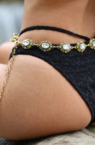 Gold anklet with rhinestones on a person's ankle against a blurred background