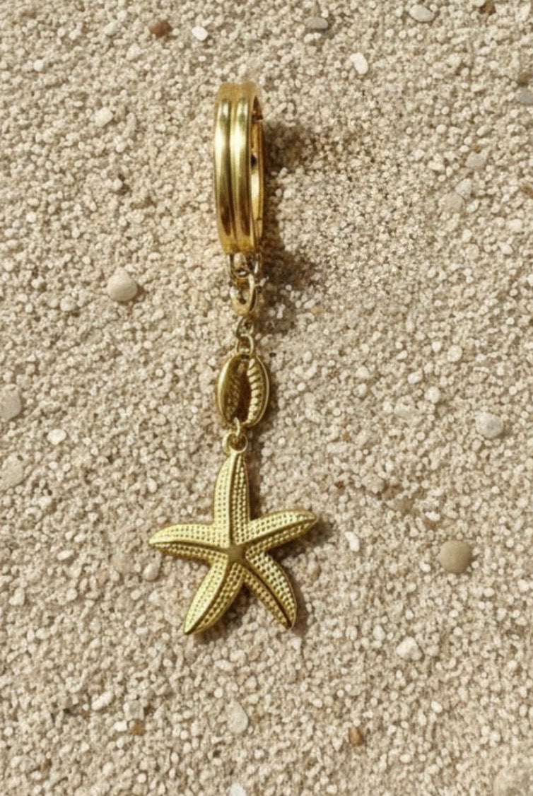 Gold charm with starfish design on a sandy background