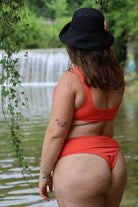 Person wearing a red bikini and black hat with a natural setting in the background