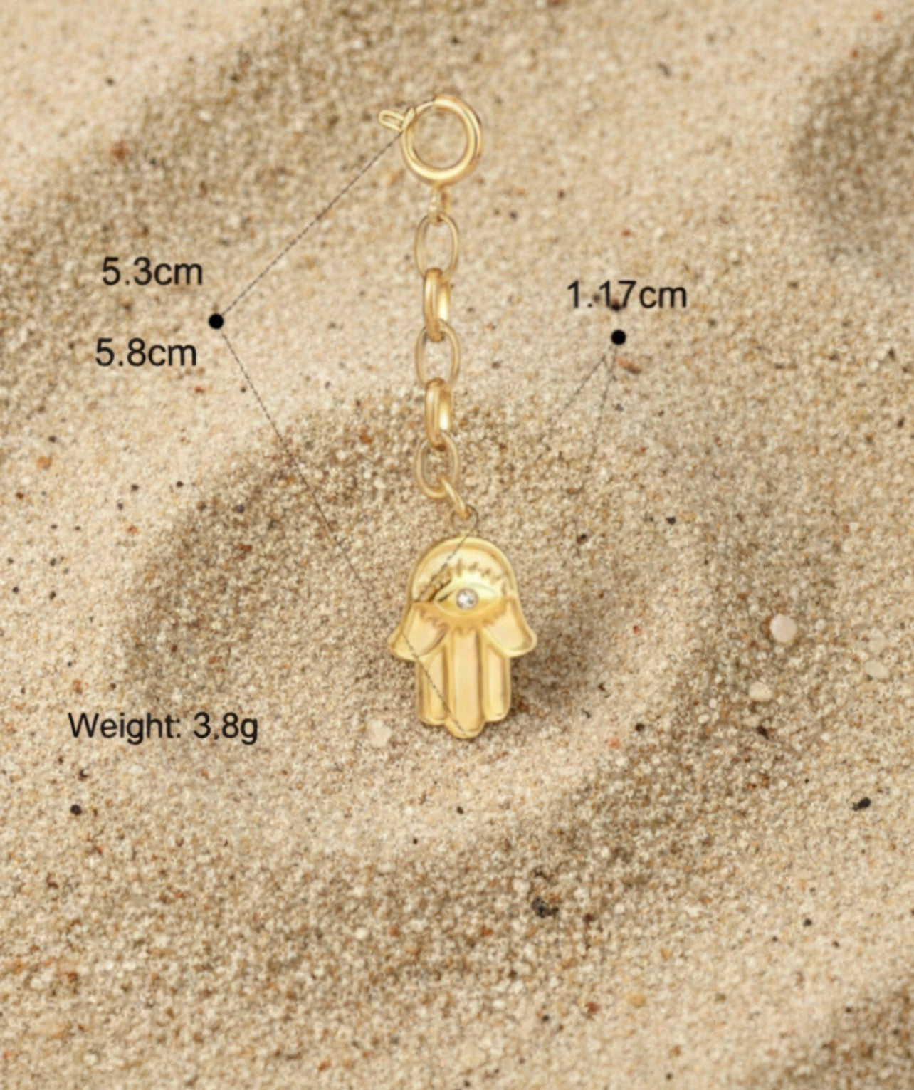 Gold Hamsa hand charm with measurements and weight on a beige background