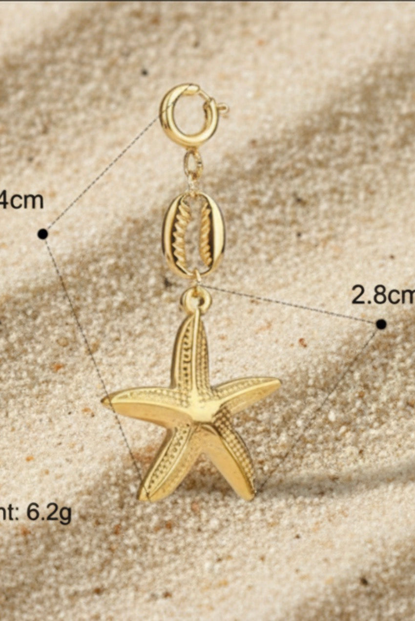 Gold starfish pendant with measurements on a sandy surface
