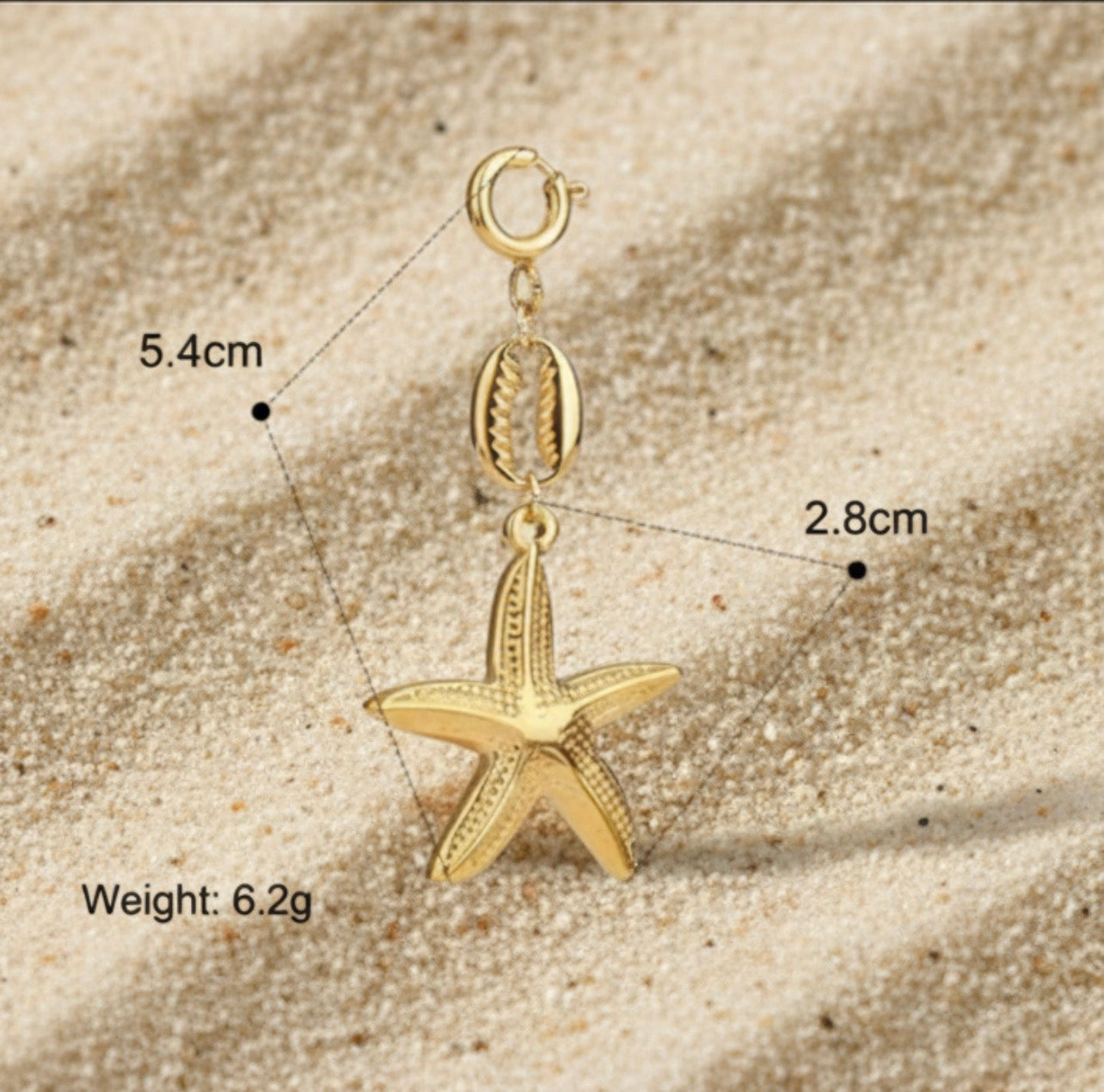 Gold starfish pendant with measurements on a sandy surface