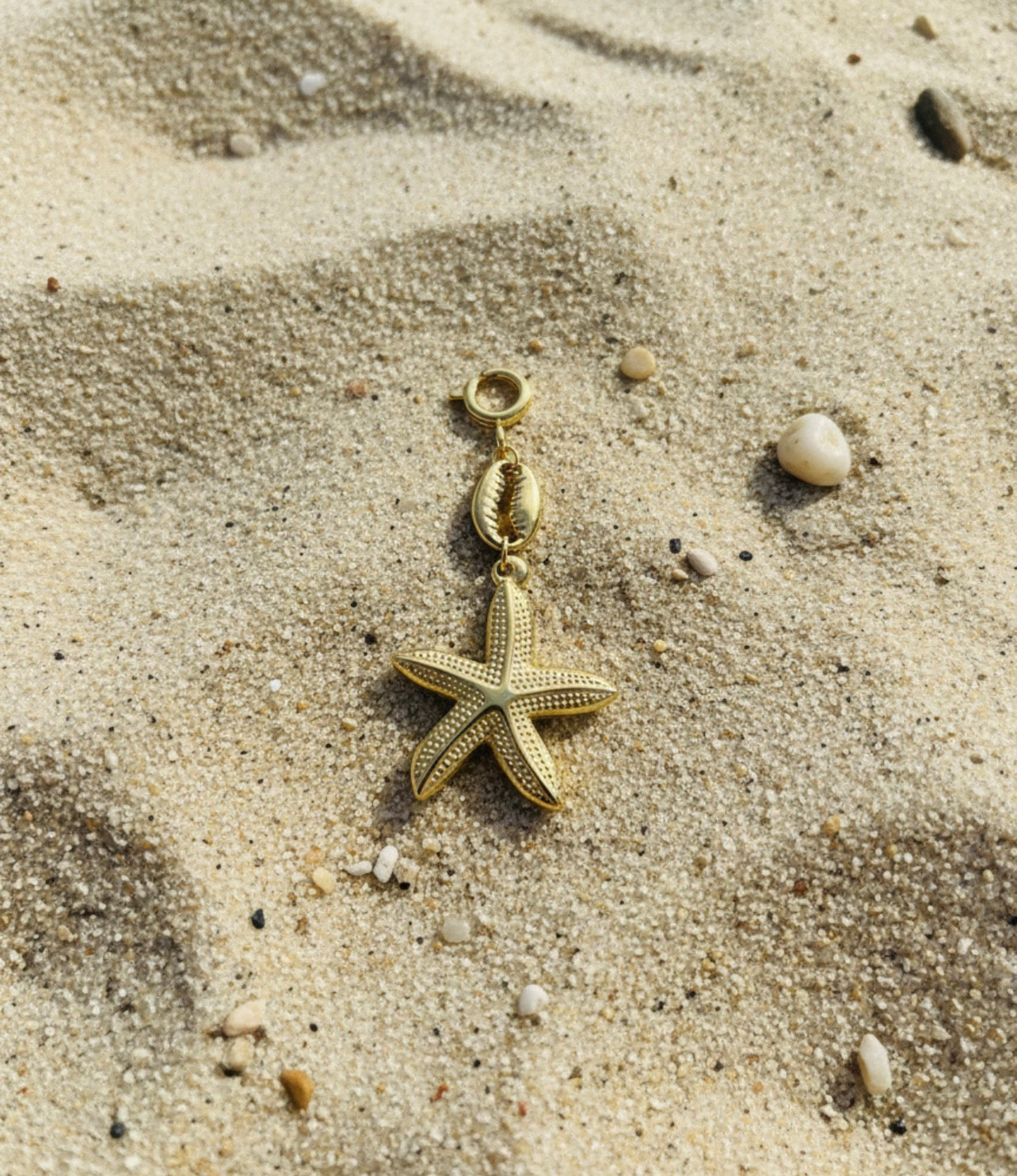 Gold starfish pendant on a sandy surface