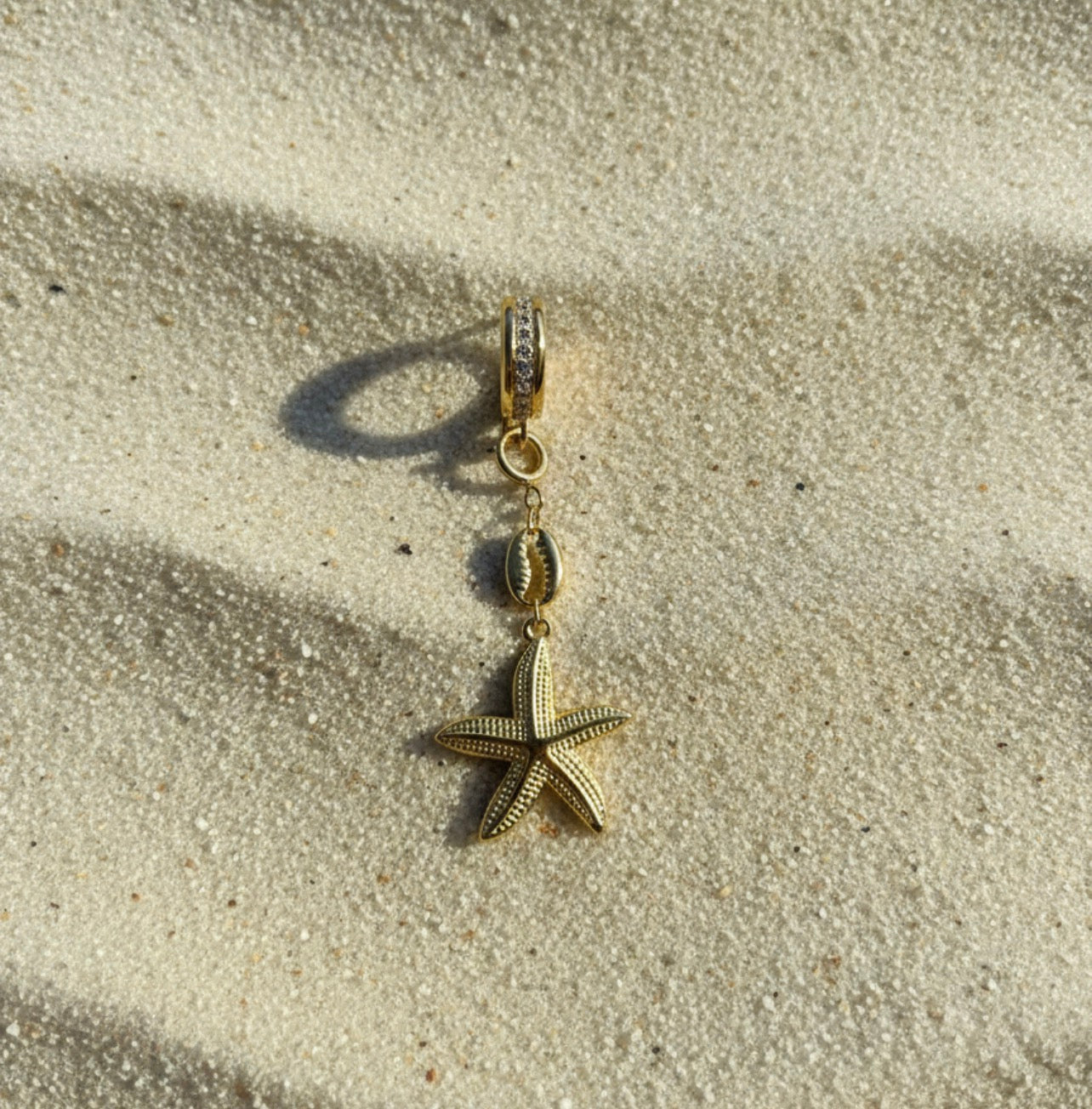 Starfish-shaped pendant on a sandy surface