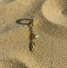 Gold charm with seahorse and shell on sand