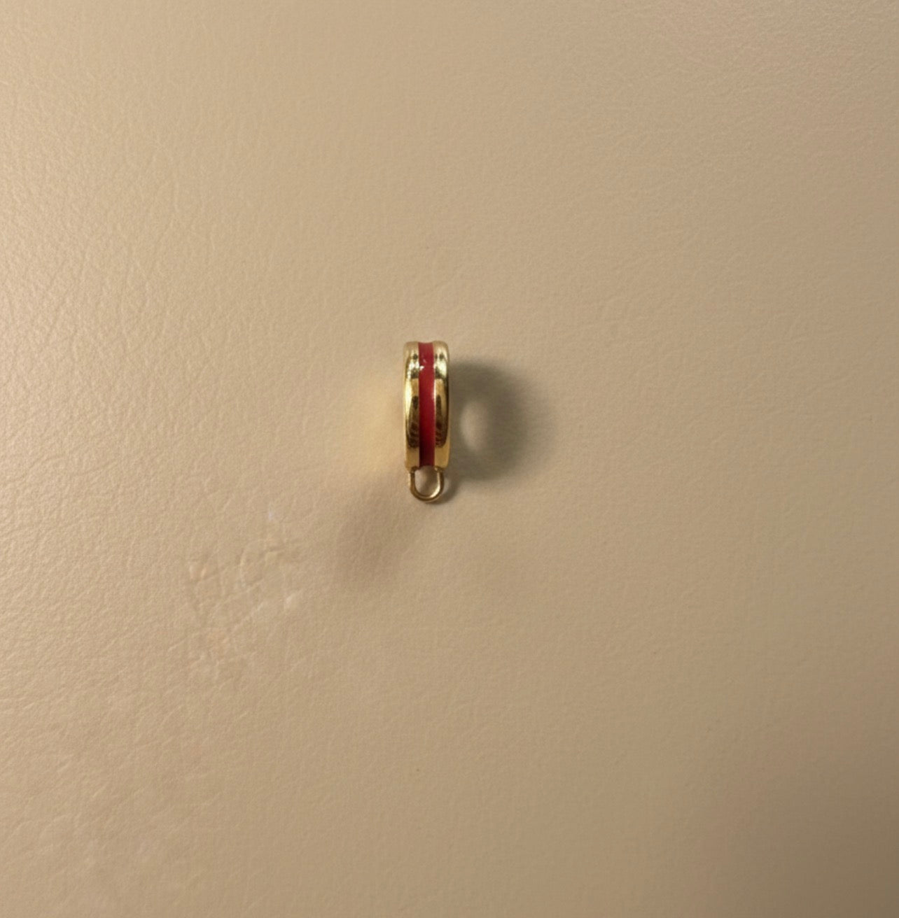 Small red and gold bikini clip on on a beige wall