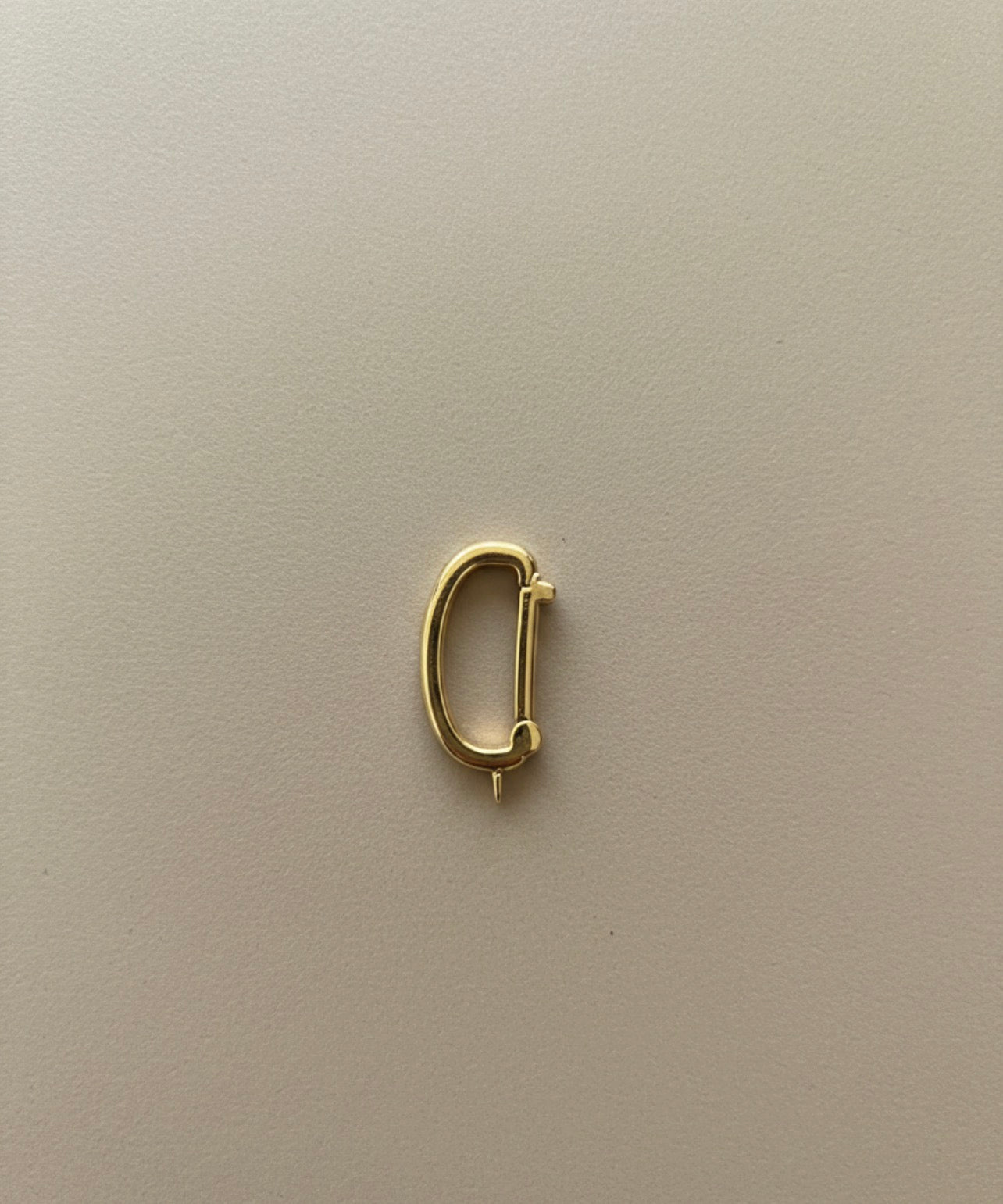 Gold bikini clip on from the side on a beige background