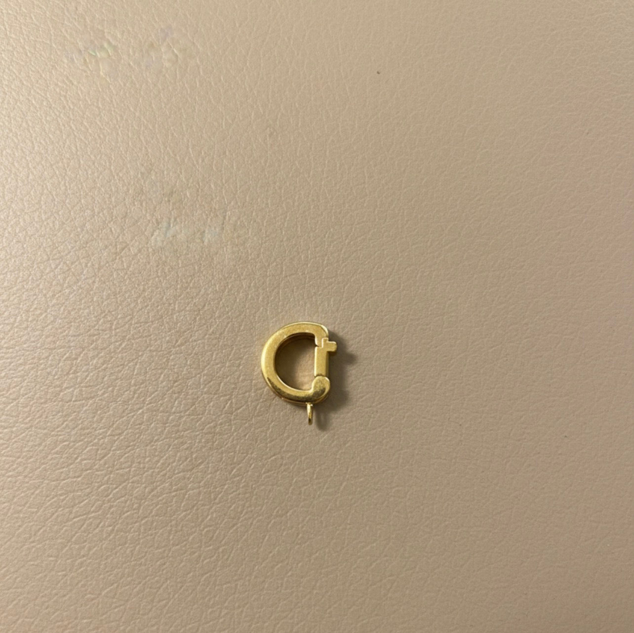 Gold bikini clip on a beige background