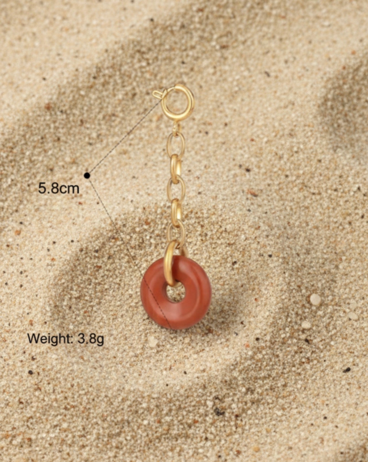 Jewelry charm with a donut-shaped pendant on a beige background